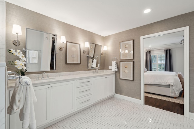 ensuite bathroom with double vanity, ensuite bathroom, baseboards, and a sink