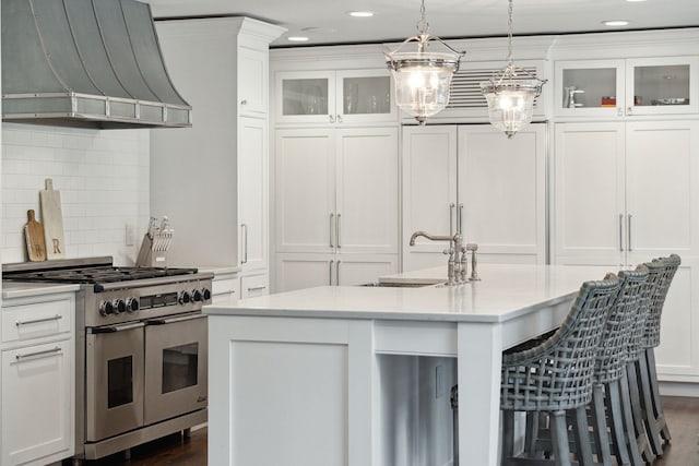 kitchen with white cabinetry, wall chimney exhaust hood, double oven range, and a sink