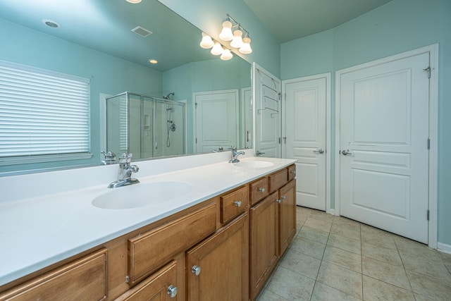 full bathroom featuring double vanity, a stall shower, a sink, and tile patterned floors