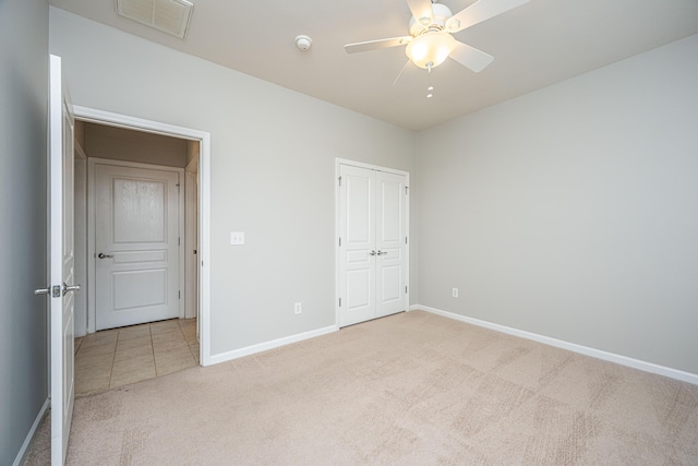 unfurnished bedroom featuring light colored carpet, a ceiling fan, baseboards, visible vents, and a closet