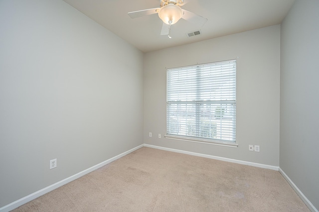 unfurnished room featuring a ceiling fan, light colored carpet, visible vents, and baseboards