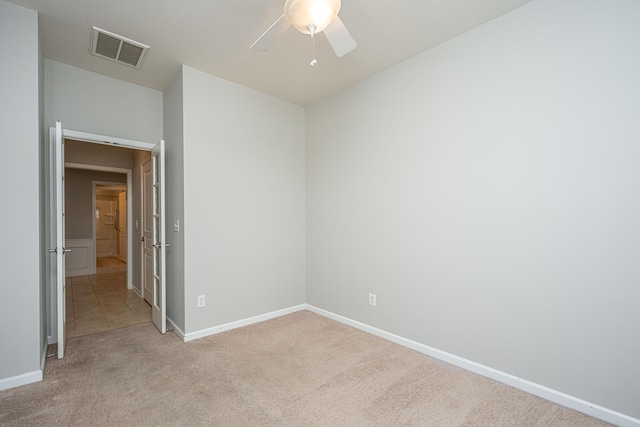 spare room with baseboards, a ceiling fan, visible vents, and light colored carpet