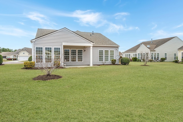 rear view of house with a shingled roof and a yard