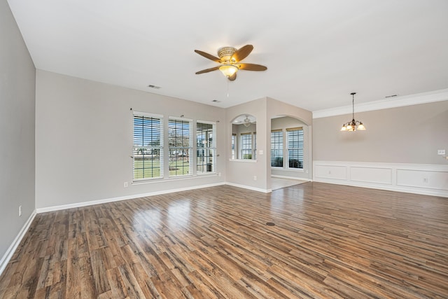 unfurnished living room featuring arched walkways, wood finished floors, baseboards, and ceiling fan with notable chandelier