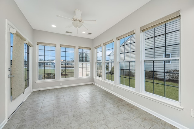 unfurnished sunroom with a ceiling fan, visible vents, and a wealth of natural light