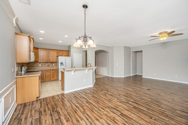 kitchen with white appliances, light wood finished floors, open floor plan, light countertops, and backsplash