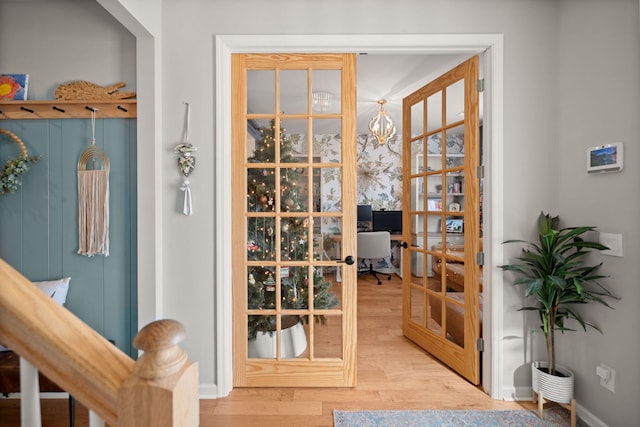 doorway to outside with french doors, an inviting chandelier, and light wood-type flooring