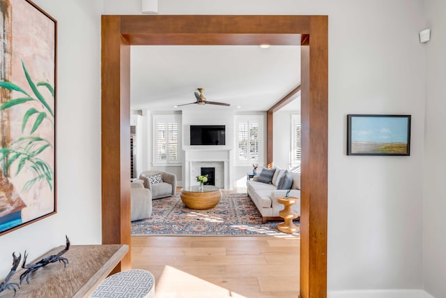 living area with wood finished floors, a high end fireplace, and a ceiling fan