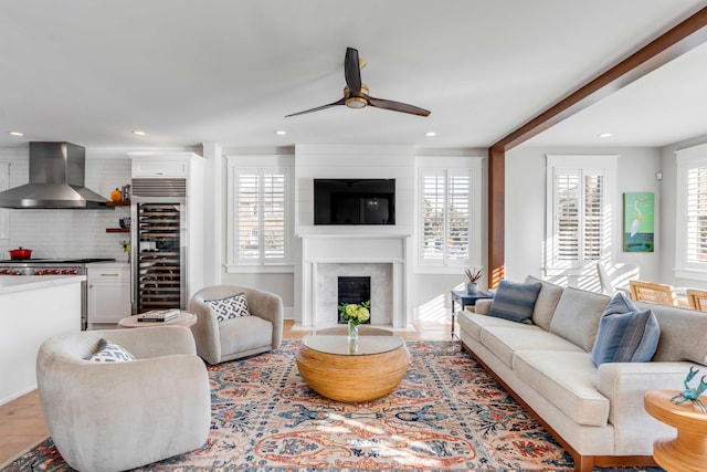 living room featuring a healthy amount of sunlight, beverage cooler, a fireplace, and recessed lighting