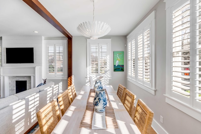 dining room with baseboards, a premium fireplace, and an inviting chandelier