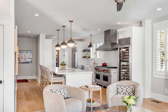 kitchen featuring a healthy amount of sunlight, range hood, visible vents, and premium appliances