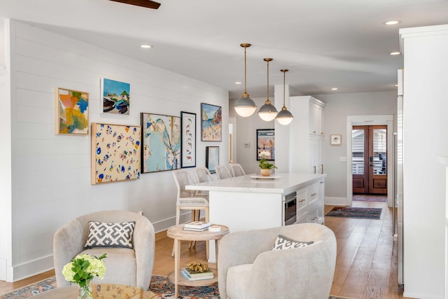 kitchen featuring light wood finished floors, a breakfast bar area, white cabinets, and recessed lighting