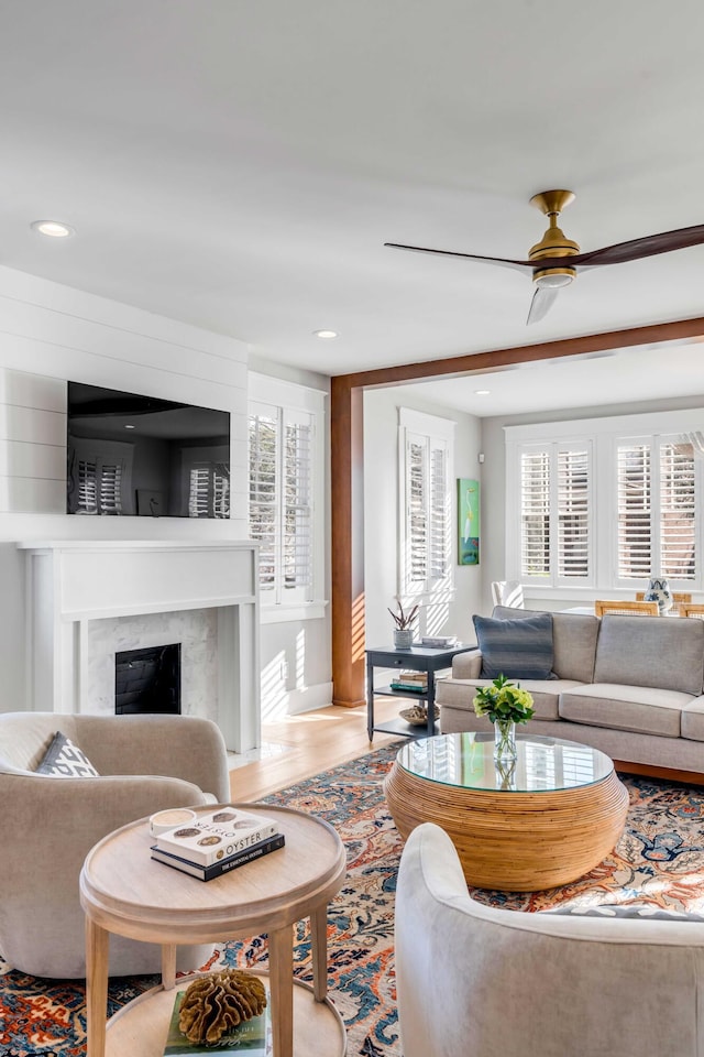 living room with light wood-type flooring, ceiling fan, a premium fireplace, and recessed lighting