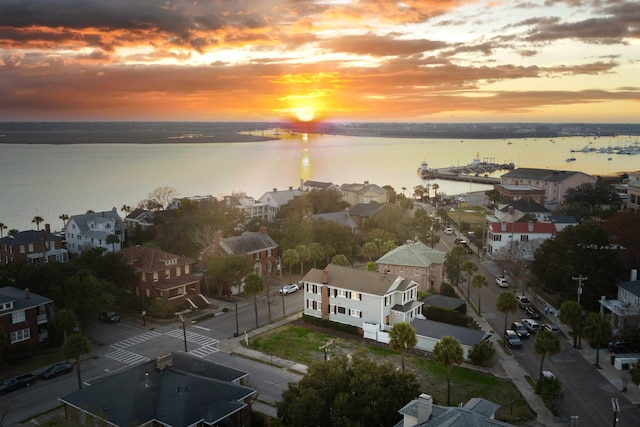 aerial view at dusk featuring a water view and a residential view