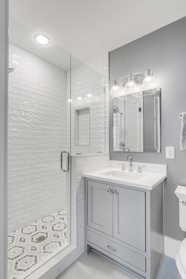 bathroom with toilet, a shower stall, tile patterned flooring, and vanity