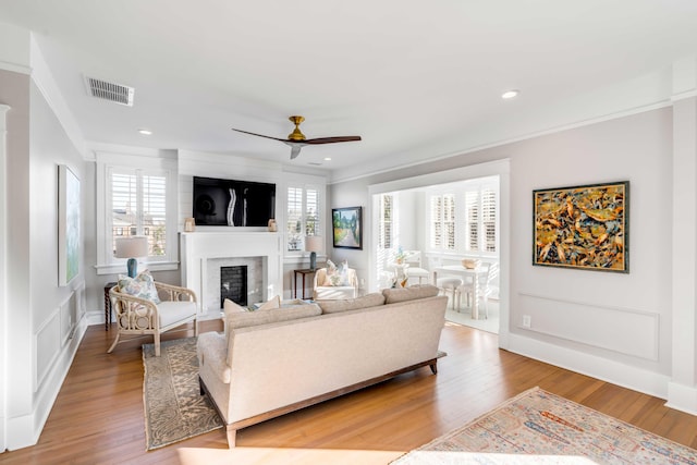 living area with light wood finished floors, plenty of natural light, a glass covered fireplace, and visible vents