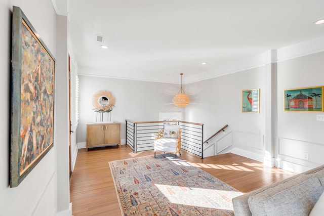 hallway featuring light wood-type flooring, baseboards, visible vents, and an upstairs landing