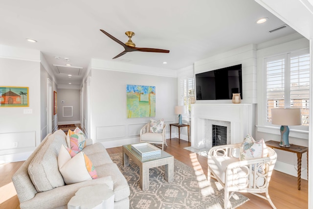 living room featuring ornamental molding, visible vents, a premium fireplace, and wood finished floors