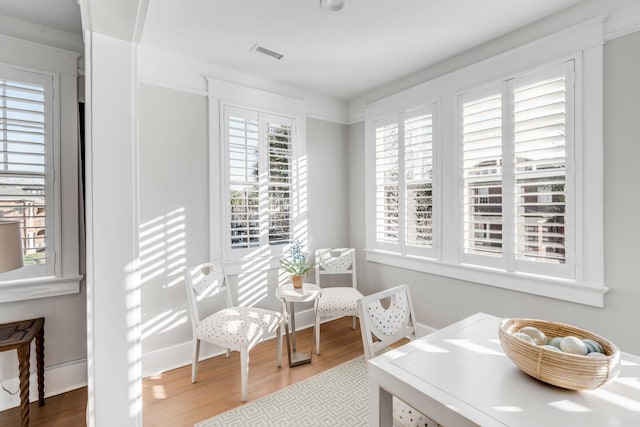 living area with baseboards, visible vents, and wood finished floors