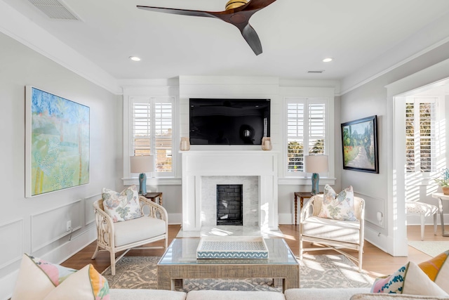 living room featuring a high end fireplace, visible vents, plenty of natural light, and wood finished floors