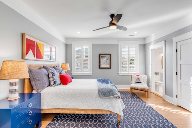 bedroom with multiple windows, wood finished floors, and baseboards