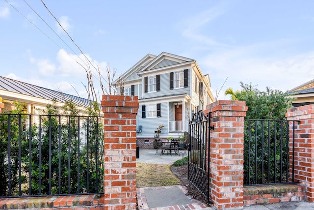 view of front of property featuring metal roof, brick siding, fence, a gate, and a standing seam roof