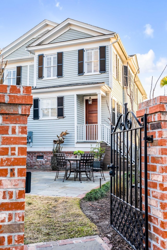 view of front facade with a gate, a patio area, and fence