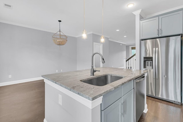 kitchen with light stone countertops, appliances with stainless steel finishes, sink, and an island with sink