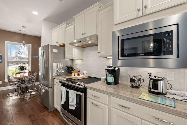 kitchen featuring appliances with stainless steel finishes, white cabinets, light stone counters, decorative backsplash, and dark wood-type flooring