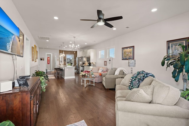 living room featuring ceiling fan with notable chandelier and dark hardwood / wood-style floors