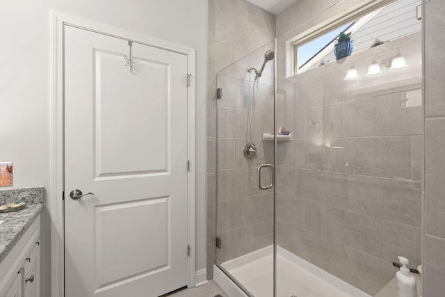 bathroom featuring a shower with door and vanity