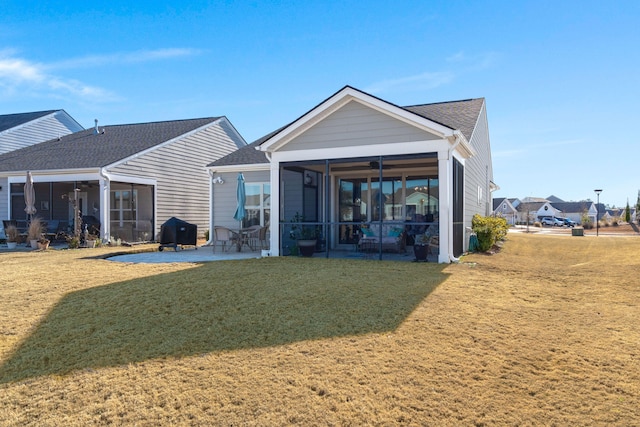 rear view of property with ceiling fan, a yard, a sunroom, and a patio area