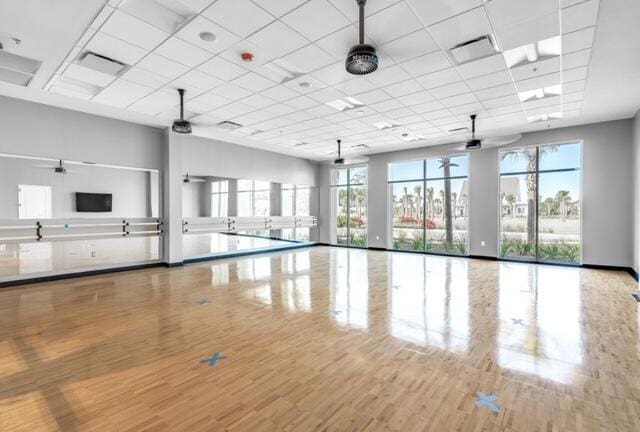 exercise area featuring a drop ceiling, ceiling fan, and wood-type flooring