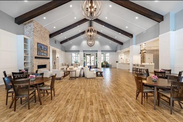 dining area featuring high vaulted ceiling, an inviting chandelier, a fireplace, and beam ceiling