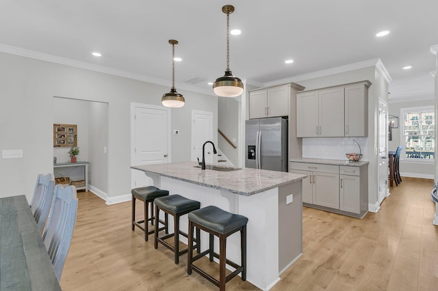 kitchen featuring gray cabinets, an island with sink, sink, and stainless steel refrigerator with ice dispenser