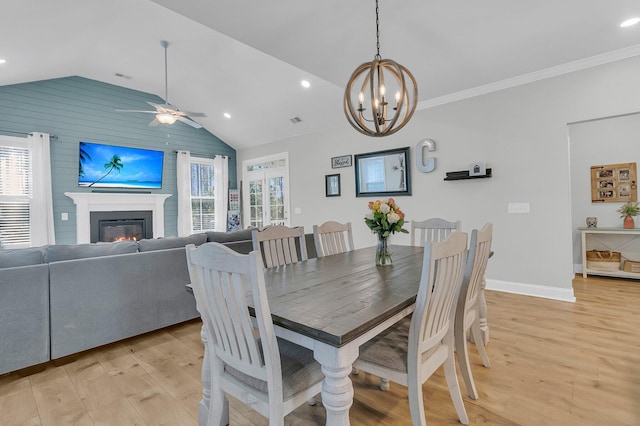 dining space with light hardwood / wood-style floors, crown molding, a wealth of natural light, and lofted ceiling