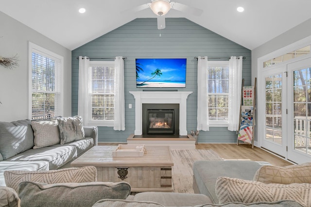 living room featuring lofted ceiling, wood walls, ceiling fan, and light hardwood / wood-style flooring