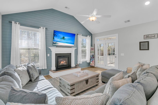 living room with ceiling fan, plenty of natural light, wood-type flooring, and lofted ceiling