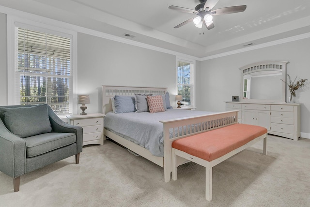 carpeted bedroom with crown molding, ceiling fan, and a raised ceiling