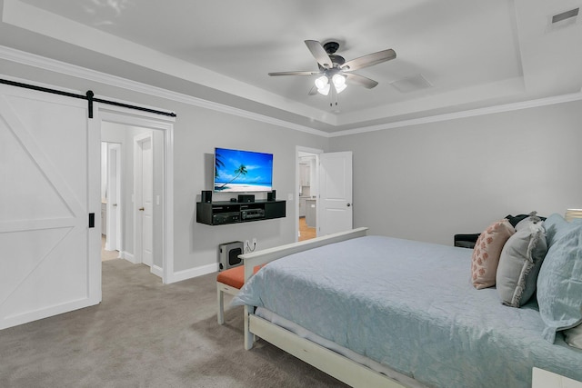 bedroom featuring carpet, a tray ceiling, a barn door, and ornamental molding