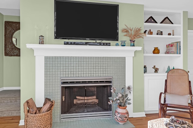 interior space with a tiled fireplace and wood-type flooring