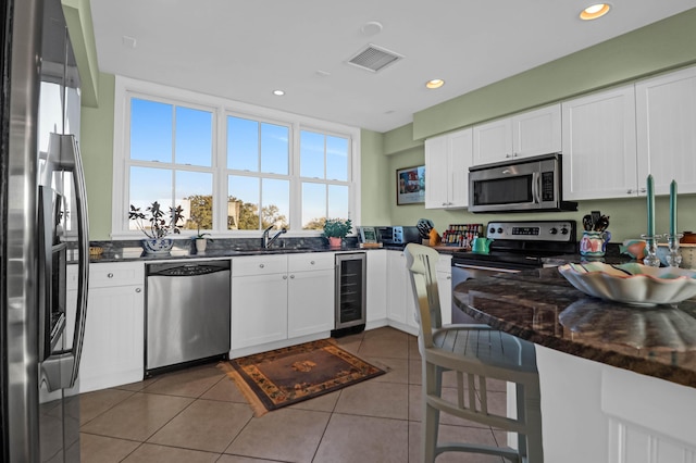 kitchen featuring wine cooler, stainless steel appliances, a breakfast bar area, and white cabinets