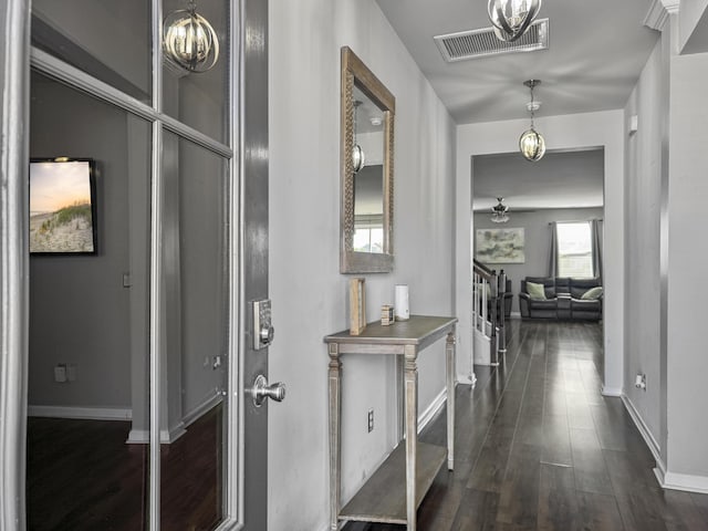 hallway with dark wood-style floors, stairway, visible vents, and baseboards