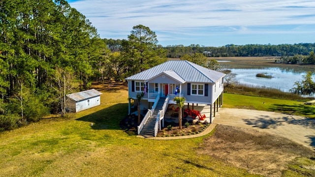 beach home with a water view, a porch, stairs, metal roof, and driveway