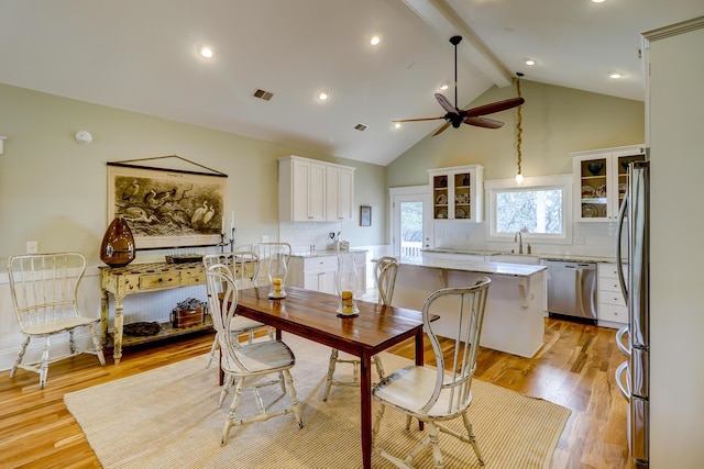 dining area with a ceiling fan, visible vents, light wood finished floors, high vaulted ceiling, and beamed ceiling