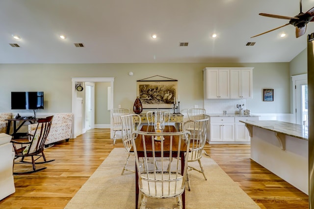 dining room featuring vaulted ceiling, visible vents, and light wood-type flooring