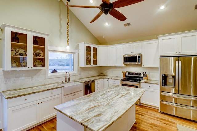 kitchen featuring visible vents, light wood-type flooring, vaulted ceiling, appliances with stainless steel finishes, and a sink