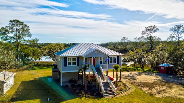 beach home with stairway, a front lawn, metal roof, and driveway