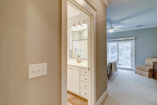 corridor featuring visible vents, ornamental molding, light colored carpet, and a sink