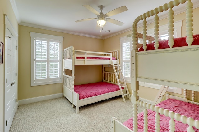 carpeted bedroom with visible vents, baseboards, ornamental molding, and a ceiling fan